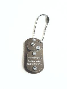 a dog tag that is attached to a metal ball chain on a white background with words written below it