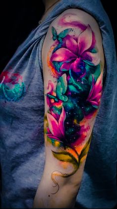 a man with a colorful tattoo on his arm and shoulder, showing the colors of flowers