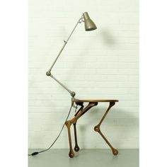 a desk lamp sitting on top of a wooden table next to a white brick wall