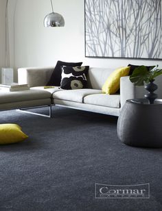 a living room with grey carpet and yellow pillows