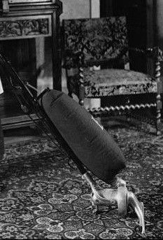 an old black and white photo of a man with a rolling suitcase in his living room