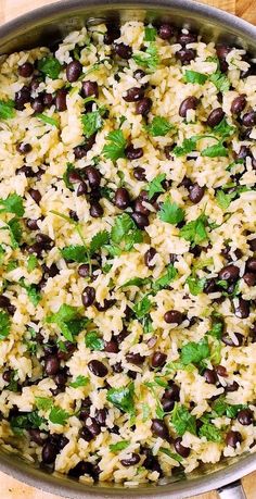 black beans and rice in a pan on a wooden table with spoons next to it