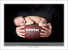 a man holding a baby in his arms with a football