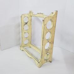 an old wooden frame with holes in the middle on a white tableclothed surface