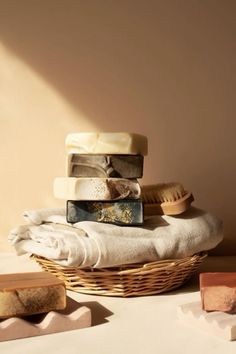 several soap bars stacked on top of each other in a wicker basket next to towels