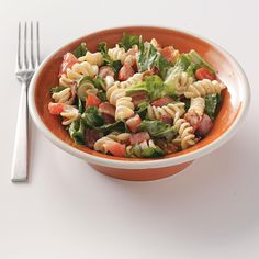 a bowl filled with pasta salad next to a fork