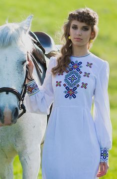 a woman standing next to a white horse