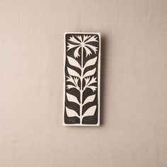 a black and white flower design on a piece of paper next to a brown wall