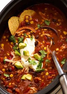 a crock pot filled with chili and tortilla chips