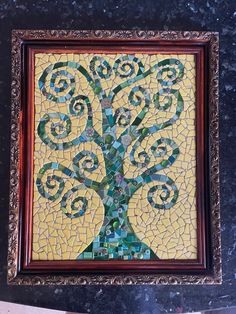 a mosaic art piece with a tree on it's side in a wooden frame