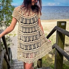 a woman is walking up some stairs near the beach wearing a crocheted dress