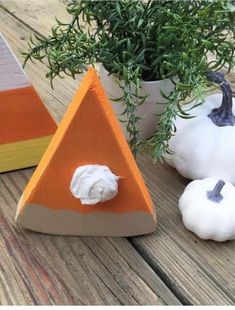 three small pumpkins are sitting on a table next to a potted plant and an orange triangle