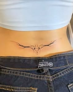 a woman's stomach with a bird tattoo on her lower back and the bottom part of her abdomen