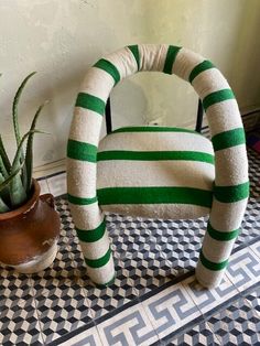 a green and white striped chair next to a potted plant