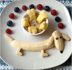 a white plate topped with fruit and a dog cut out in the shape of a banana