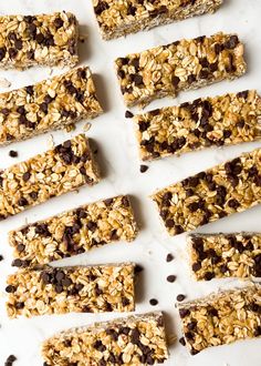 chocolate chip granola bars lined up on a white surface with oats and chocolate chips