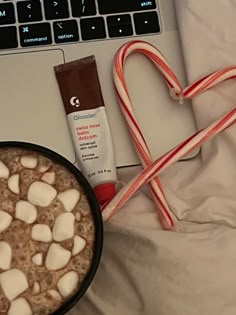 a cup of hot chocolate with marshmallows next to a laptop