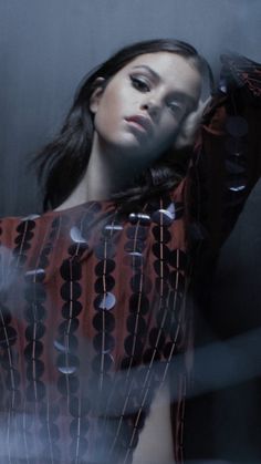 a woman is posing with her arms behind her head and wearing a patterned shirt over her shoulders