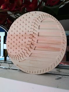 a wooden baseball shaped object sitting on top of a window sill next to flowers