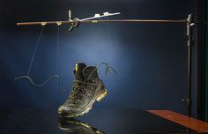 a pair of shoes hanging from a clothes line on top of a wooden table in front of a blue background