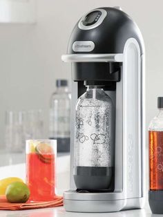 a soda machine sitting on top of a counter next to some lemons and limes