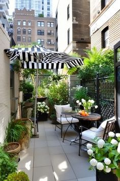 an outdoor patio with tables, chairs and umbrellas in the middle of city buildings