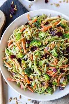 broccoli slaw salad with cranberries and nuts in a white bowl