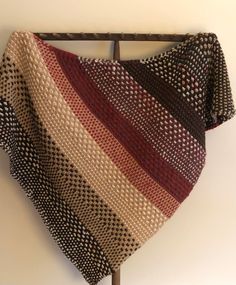 a multicolored knitted shawl hanging on a coat rack in a room