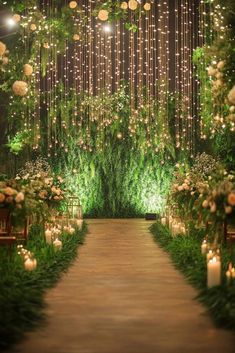 an outdoor ceremony with candles and greenery on the aisle, surrounded by white flowers