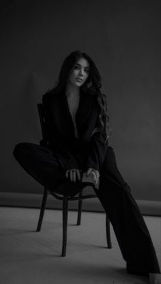 a woman sitting on top of a chair in a black and white photo with her legs crossed