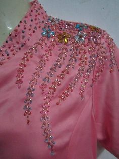 the back of a pink dress with beading and sequins on it's neck