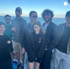 a group of people standing next to each other near the ocean