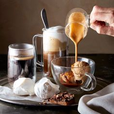 a person pours coffee into a glass cup with marshmallows and chocolate