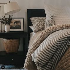 a bedroom with a bed, night stand and lamp on the side table in front of it