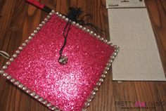 a pink and silver square shaped object sitting on top of a wooden floor next to a pair of scissors