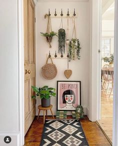 an entryway with hanging plants and potted plants on the wall next to a rug