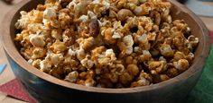 a wooden bowl filled with popcorn on top of a table