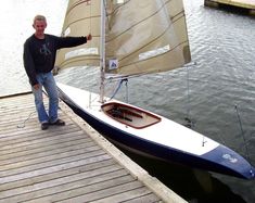 a man standing on a dock next to a sailboat