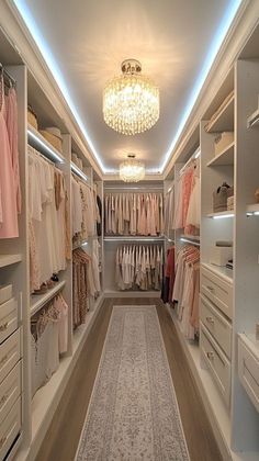 a walk in closet filled with lots of white drawers and clothes hanging on the walls