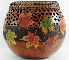 a ceramic pot with leaves painted on it's side and holes in the top