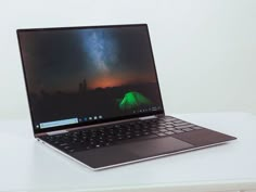 an open laptop computer sitting on top of a white table next to a green tent