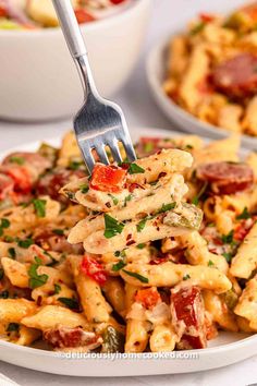 a fork full of pasta with sausage and tomatoes on it, ready to be eaten