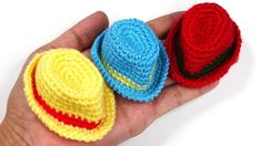 three crocheted hats are in the palm of a person's hand on a white background