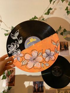 a hand holding an orange and black record with flowers painted on it