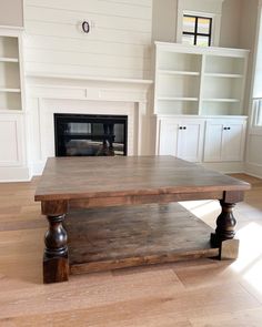 an empty living room with a fireplace and built - in bookcases