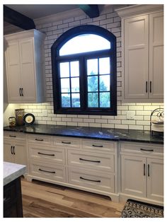 a large kitchen with white cabinets and black counter tops is pictured in this image from the front