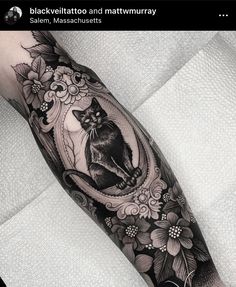 a black and white cat sitting on top of a mirror with flowers in it's frame