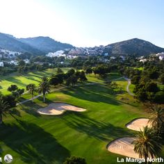 an aerial view of a golf course with palm trees and mountains in the back ground