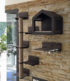 a cat tree is mounted to the side of a brick wall with shelves on it