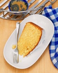 a piece of cake on a white plate with a fork and blue checkered napkin